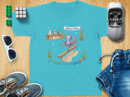Turquoise t-shirt featuring an octopus on a balance beam and "Ocean Olympics" text.