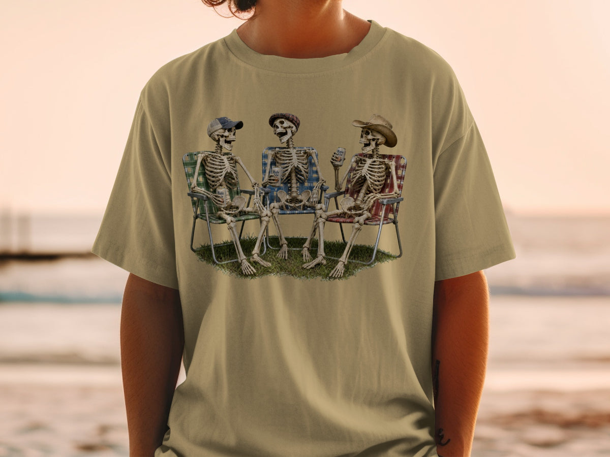 Three skeletons sit in lawn chairs on grass, holding drinks.