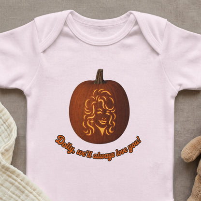 Baby onesie with a carved pumpkin featuring Dolly Parton and text "Dolly, we'll always love you!".