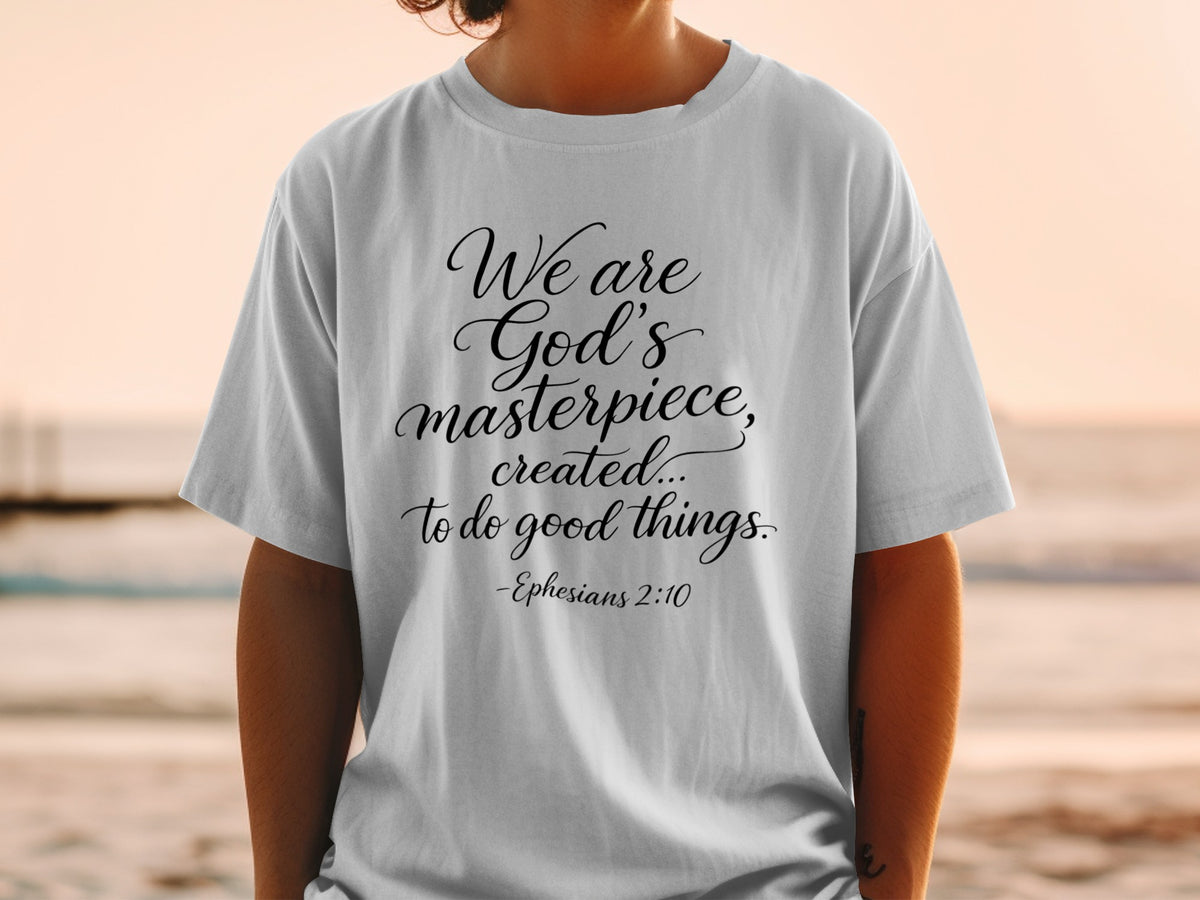 White t-shirt with black cursive text: "We are God's masterpiece, created... to do good things. -Ephesians 2:10"