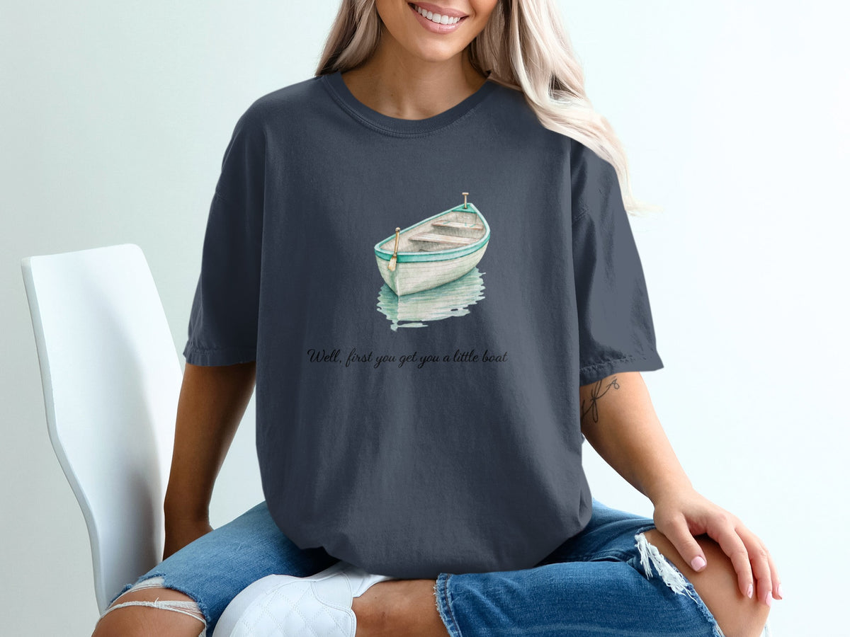 Dark grey t-shirt with watercolor boat graphic and text "Well, first you get you a little boat."