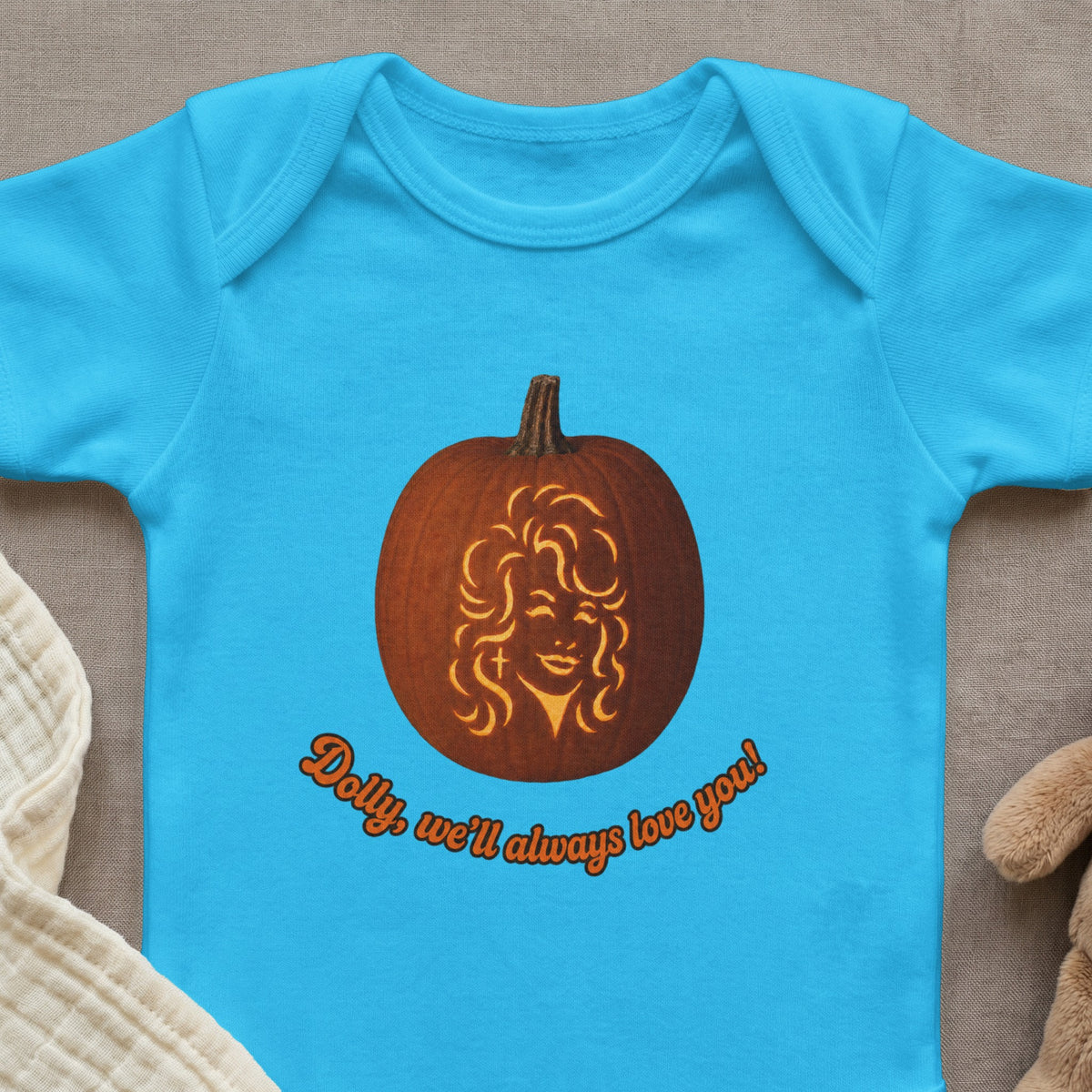 Light blue baby onesie with a carved pumpkin featuring a woman's face and text.