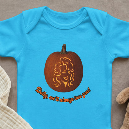 Light blue baby onesie with a carved pumpkin featuring a woman's face and text.