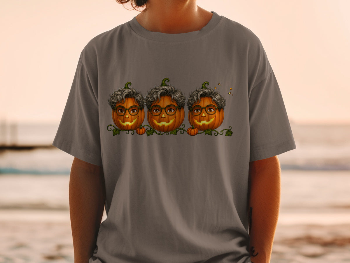 Three smiling pumpkins with glasses and curly hair on a gray t-shirt.