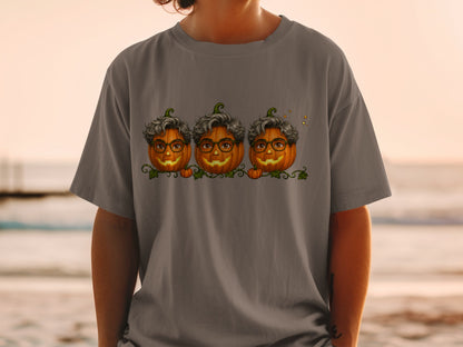 Three smiling pumpkins with glasses and curly hair on a gray t-shirt.