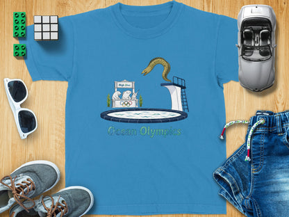 Blue t-shirt graphic with cartoon eel on diving board and text "Ocean Olympics".