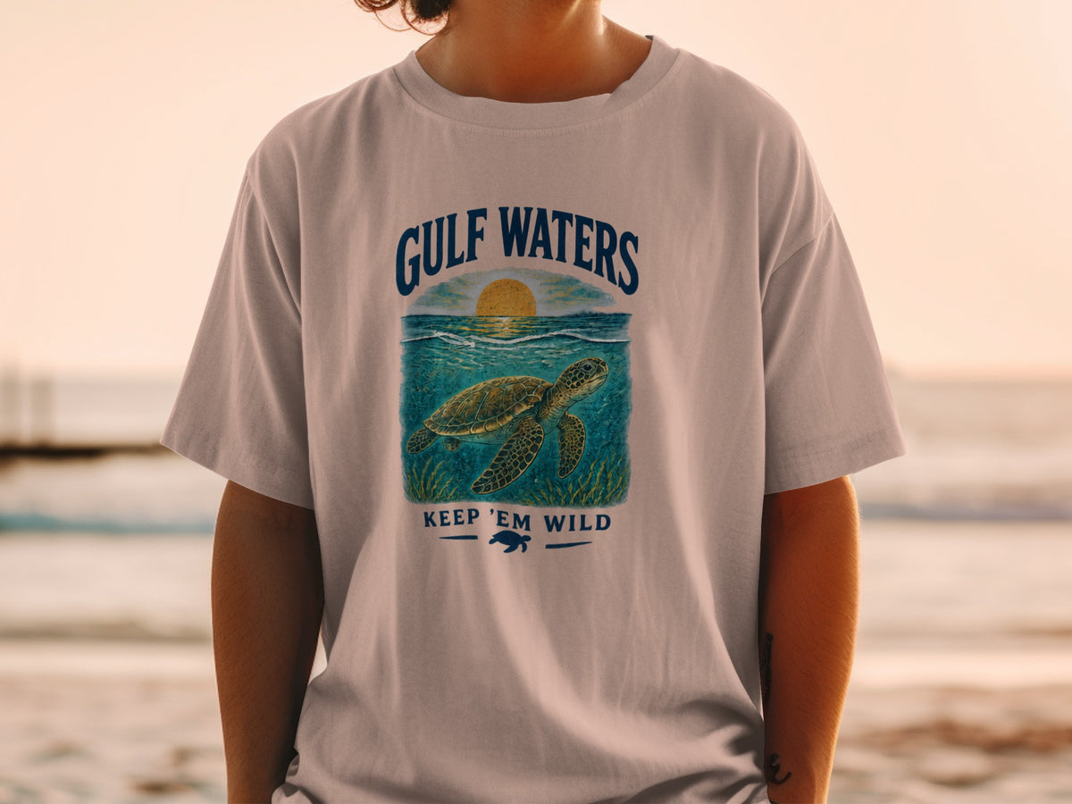 Light gray t-shirt with "GULF WATERS" text above a sea turtle and "KEEP 'EM WILD" text.