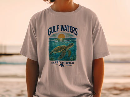 Light gray t-shirt with "GULF WATERS" text above a sea turtle and "KEEP 'EM WILD" text.