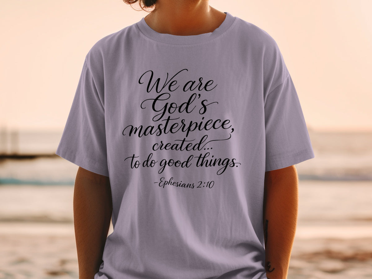 Lavender t-shirt with black script text: "We are God's masterpiece, created...to do good things. -Ephesians 2:10"