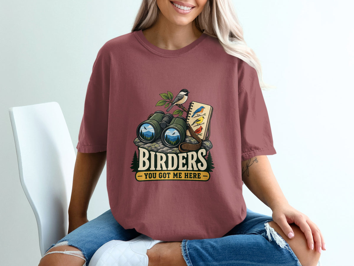 Birders You Got Me Here graphic with binoculars, notebook, and birds on maroon t-shirt.