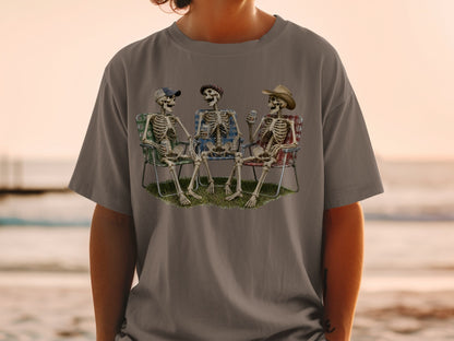 Three skeletons sit in camping chairs, two holding cans of "Bale Ale."