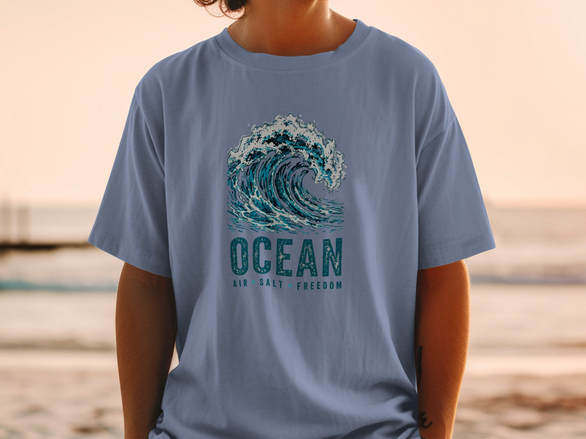 T-shirt with a graphic of a breaking wave and text reading "OCEAN AIR SALT FREEDOM".