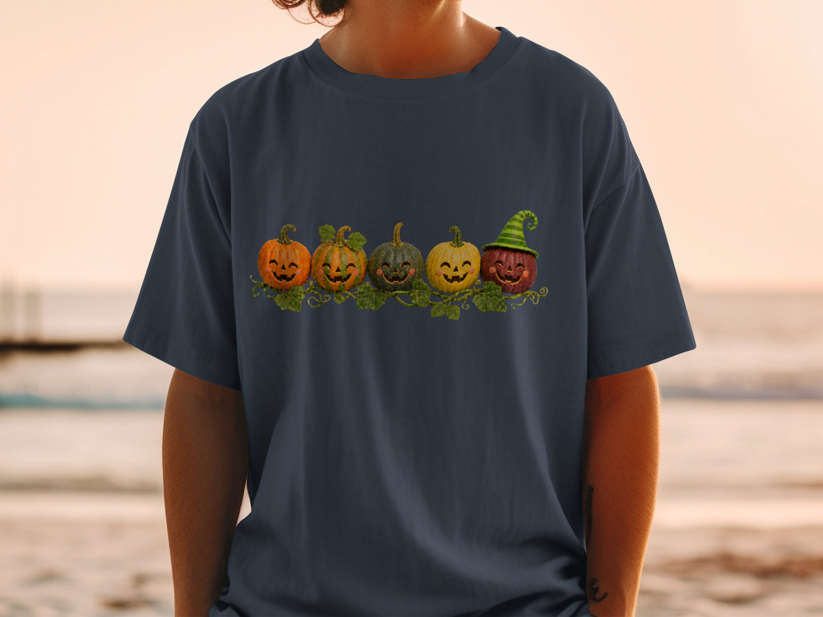 Five cartoon pumpkins with happy faces and vine accents on a dark t-shirt.