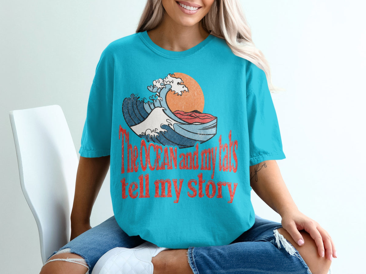 Turquoise t-shirt with a wave graphic and text "The ocean and my tats tell my story".