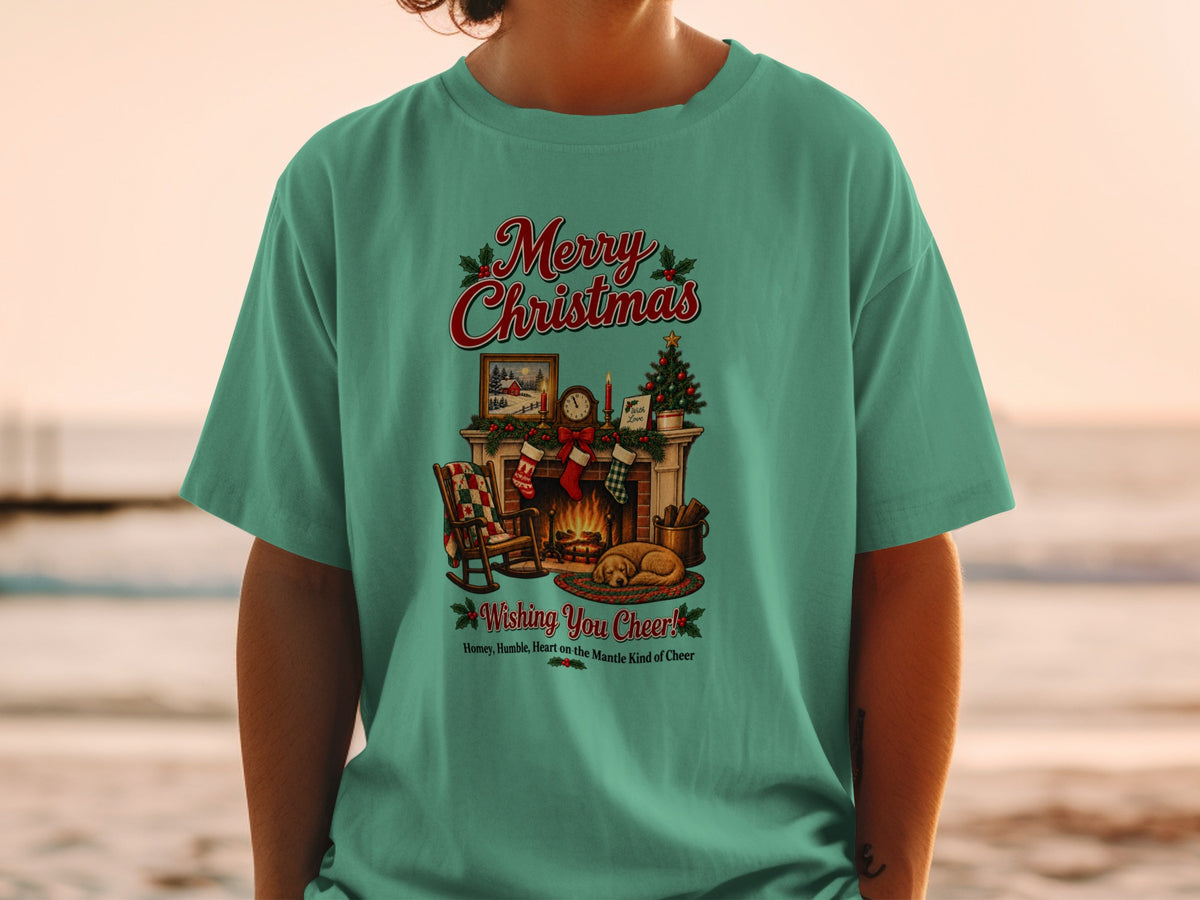Green t-shirt with a Merry Christmas graphic featuring a fireplace, rocking chair, and sleeping dog.