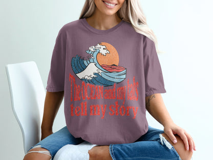Purple t-shirt with vintage ocean wave graphic and text "The ocean and my tats tell my story".