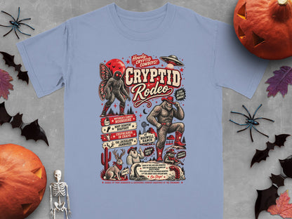 Light blue t-shirt featuring a "Cryptid Rodeo" design with Bigfoot, Mothman, and other creatures.