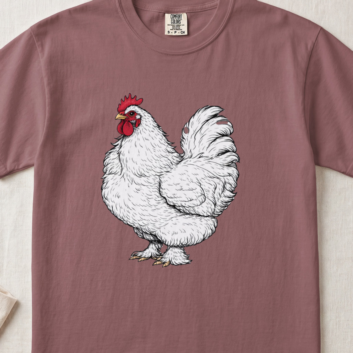 Dusty rose short-sleeved t-shirt featuring a detailed white rooster illustration on the chest.