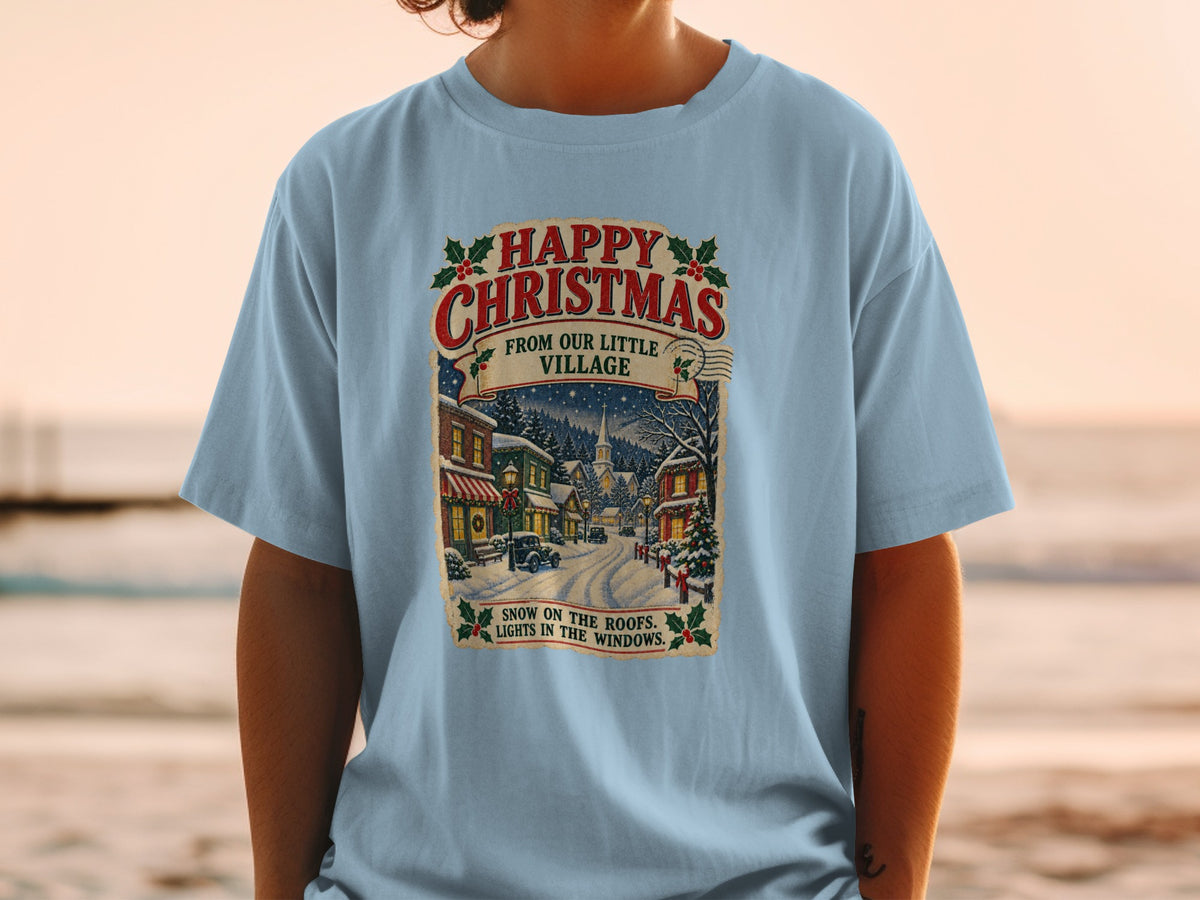 Light blue t-shirt with a vintage Christmas village graphic and text.