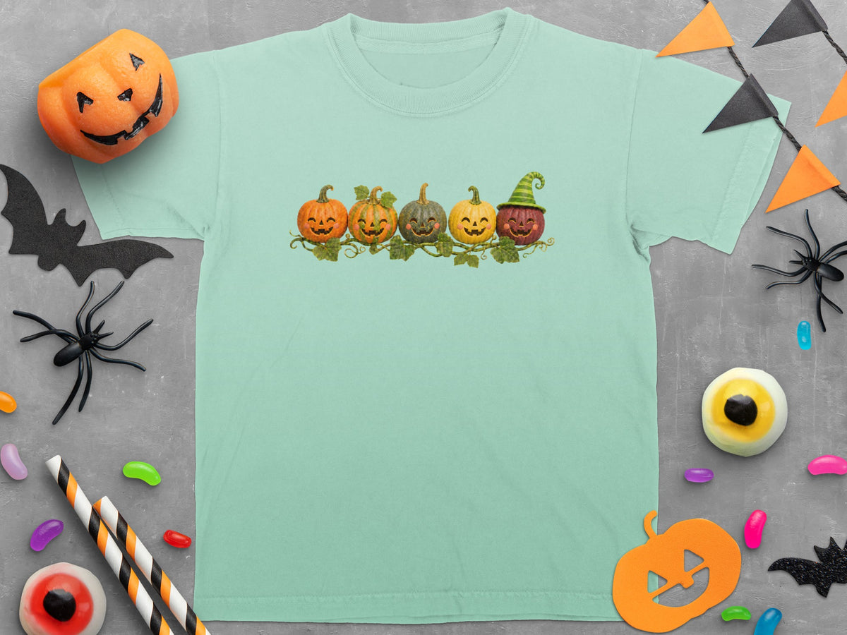 Mint green t-shirt with a row of five smiling cartoon pumpkins.