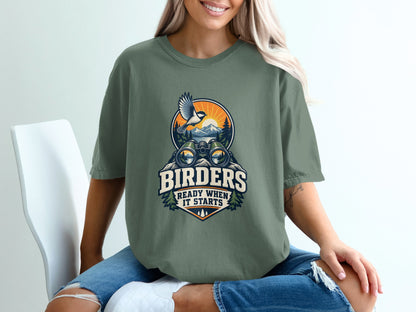 T-shirt graphic with binoculars, bird, mountains, and text "BIRDERS READY WHEN IT STARTS".