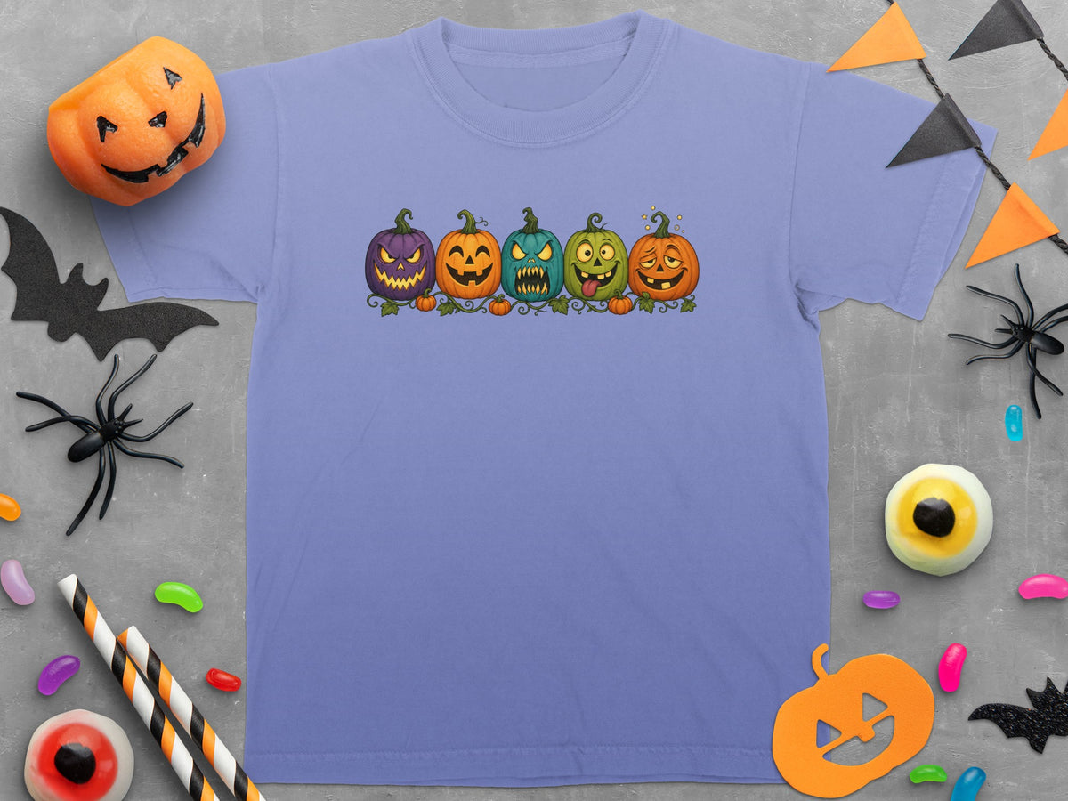 Purple t-shirt with five cartoon pumpkins in a row, surrounded by Halloween decorations.