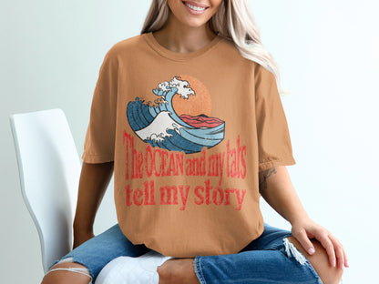 Orange t-shirt with graphic wave, sun, and text "The OCEAN and my tats tell my story".