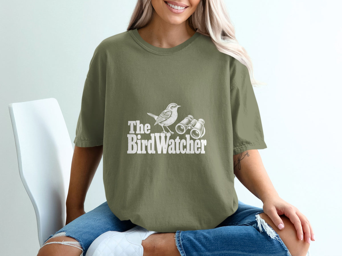 Olive green t-shirt with "The BirdWatcher" text, bird, and binoculars graphic.