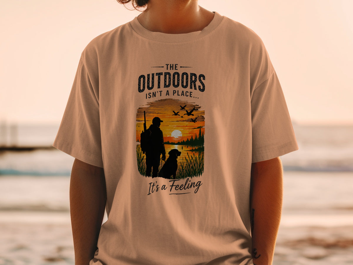 T-shirt with graphic of hunter, dog, and sunset scene with text "The Outdoors Isn't a Place... It's a Feeling."