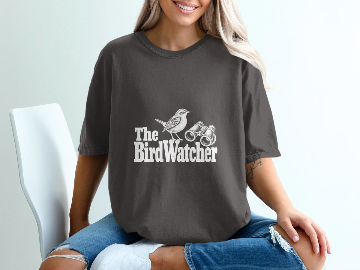 Dark grey t-shirt with white "The Bird Watcher" text and bird graphic.