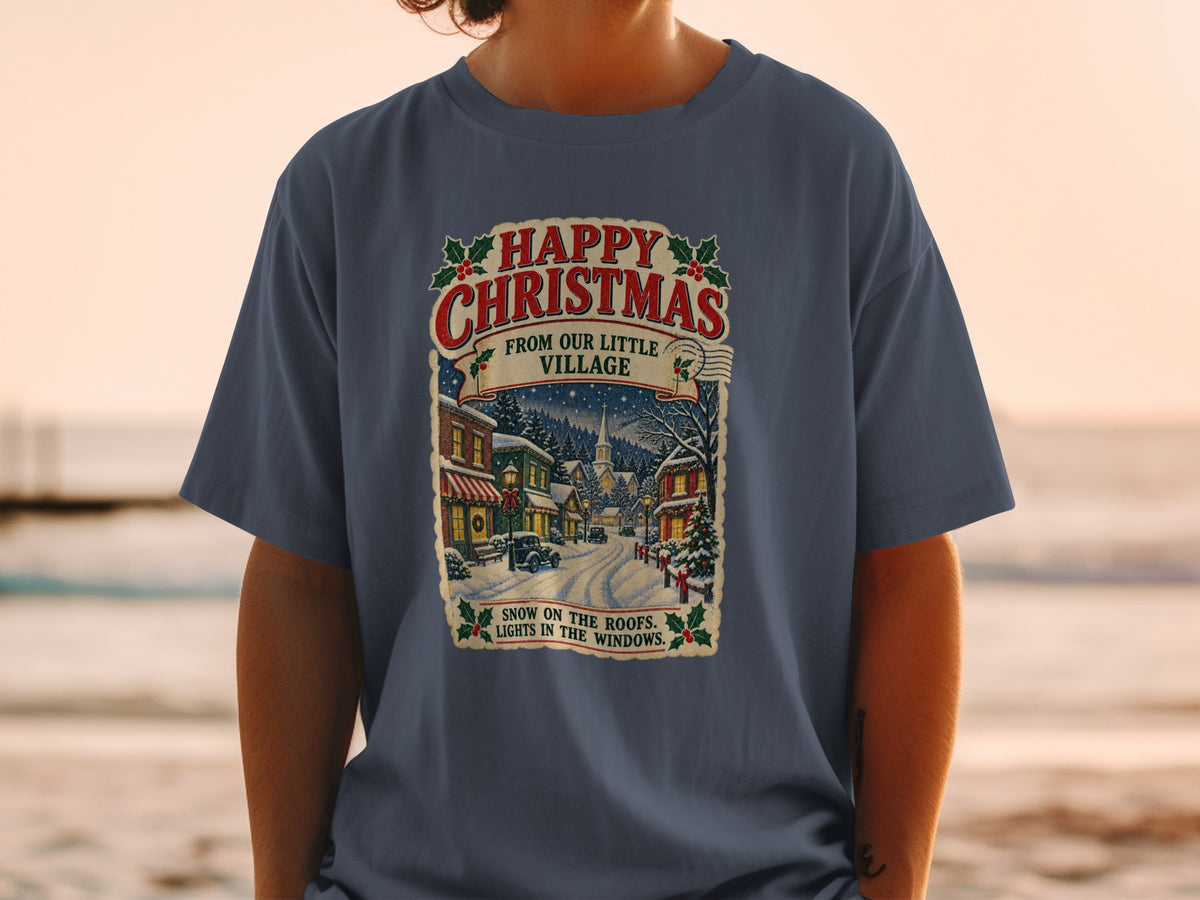 T-shirt graphic with "Happy Christmas From Our Little Village" and a snowy village scene.