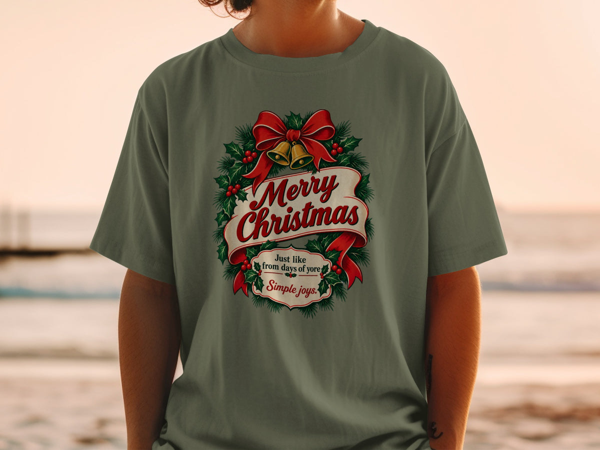 Olive green t-shirt with a Christmas wreath graphic, red bow, bells, and text.