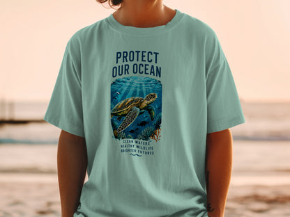 Light blue t-shirt with a sea turtle illustration and text reading "PROTECT OUR OCEAN" and "CLEAN WATERS HEALTHY WILDLIFE BRIGHTER FUTURES".