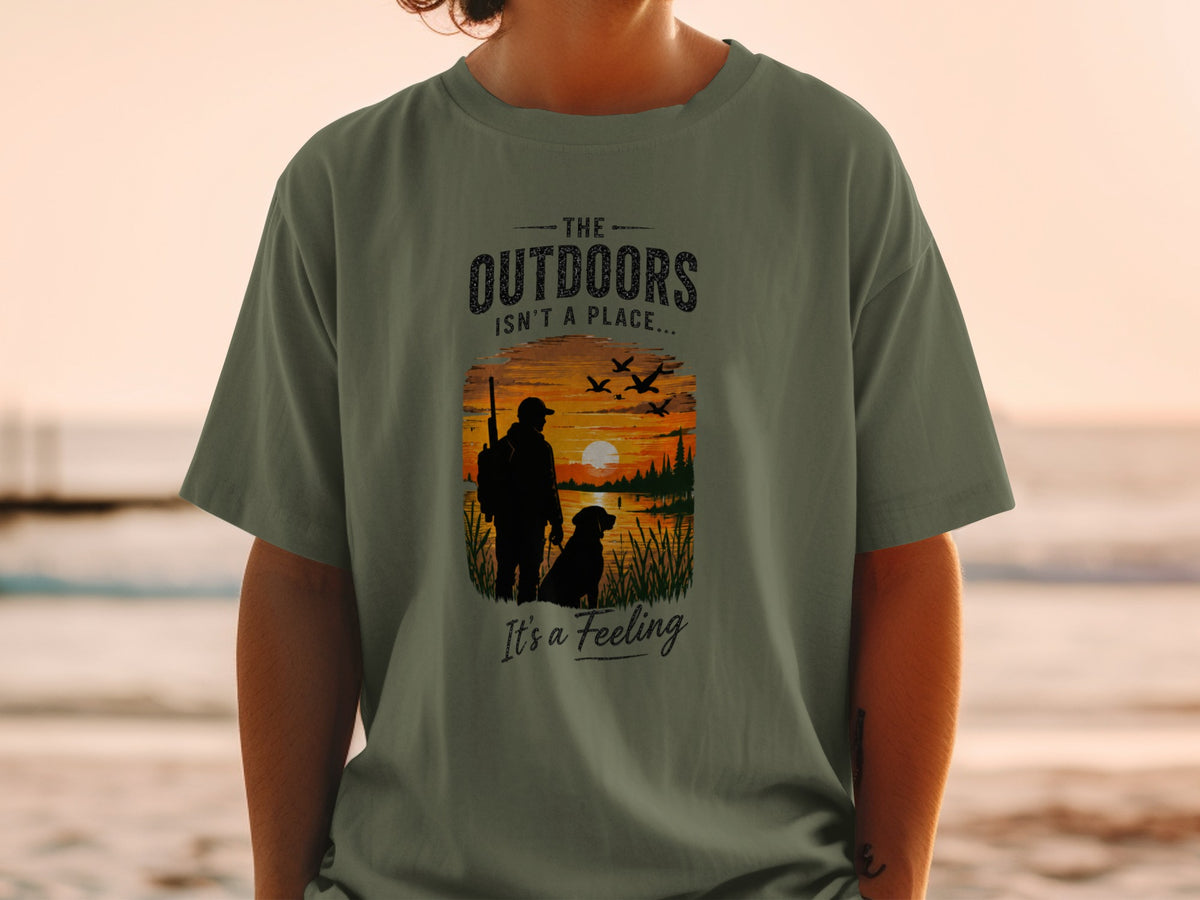 T-shirt with graphic: hunter, dog, sunset over lake, and text "The Outdoors Isn't a Place... It's a Feeling"