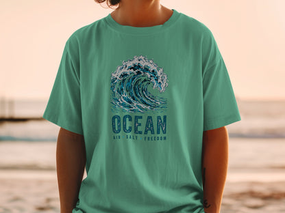 Teal t-shirt with crashing wave graphic and text "OCEAN AIR SALT FREEDOM".