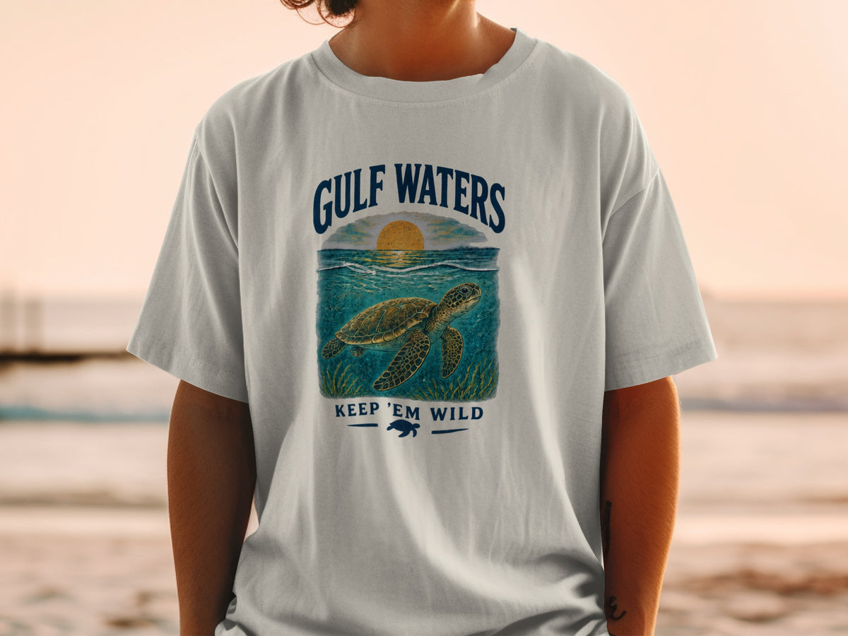 Light gray t-shirt with a graphic of a sea turtle and sunset, "GULF WATERS KEEP 'EM WILD" text.