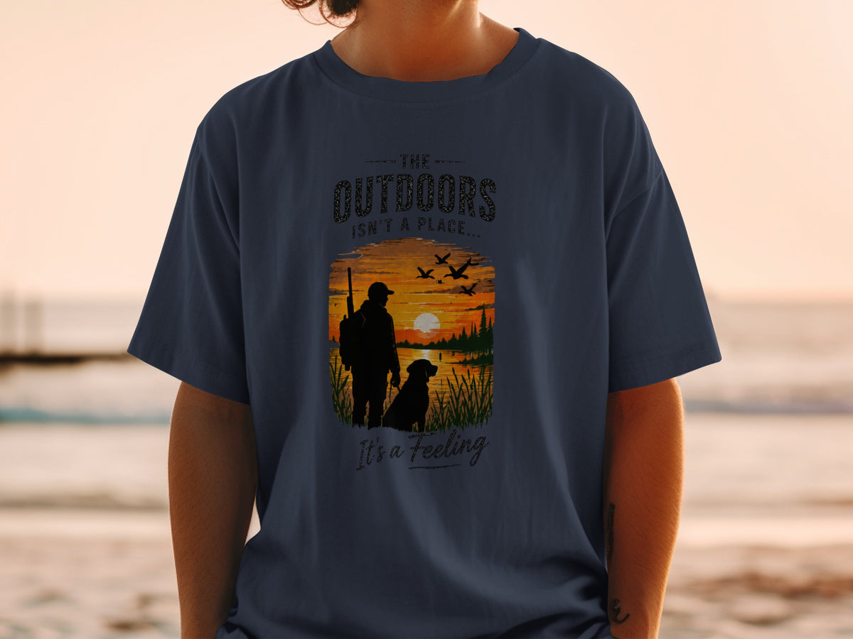 T-shirt with silhouette of hunter and dog at sunset, "The Outdoors Isn't a Place..." text.