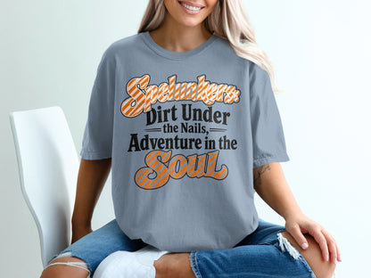 "Spelunkers: Dirt Under the Nails, Adventure in the Soul" text graphic on a blue t-shirt.