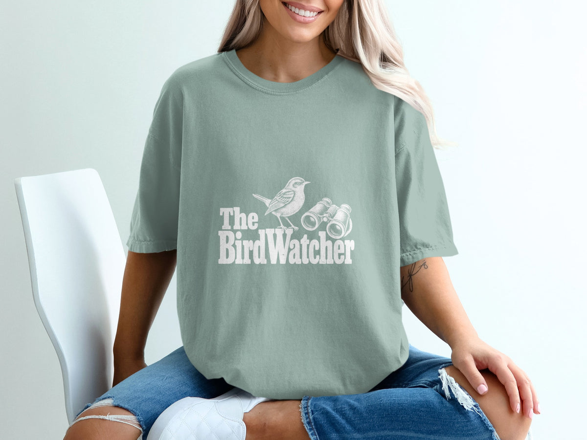 Light green t-shirt with white graphic of a bird and binoculars, text reads "The BirdWatcher".