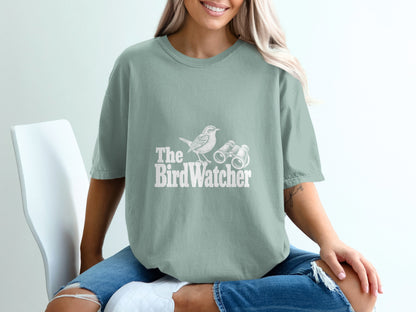 Light green t-shirt with white graphic of a bird and binoculars, text reads "The BirdWatcher".