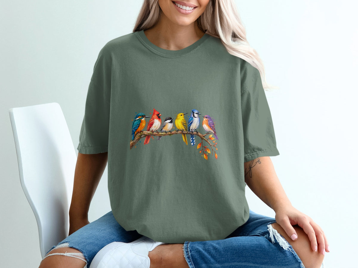 Green t-shirt featuring a watercolor illustration of seven colorful birds on a branch.