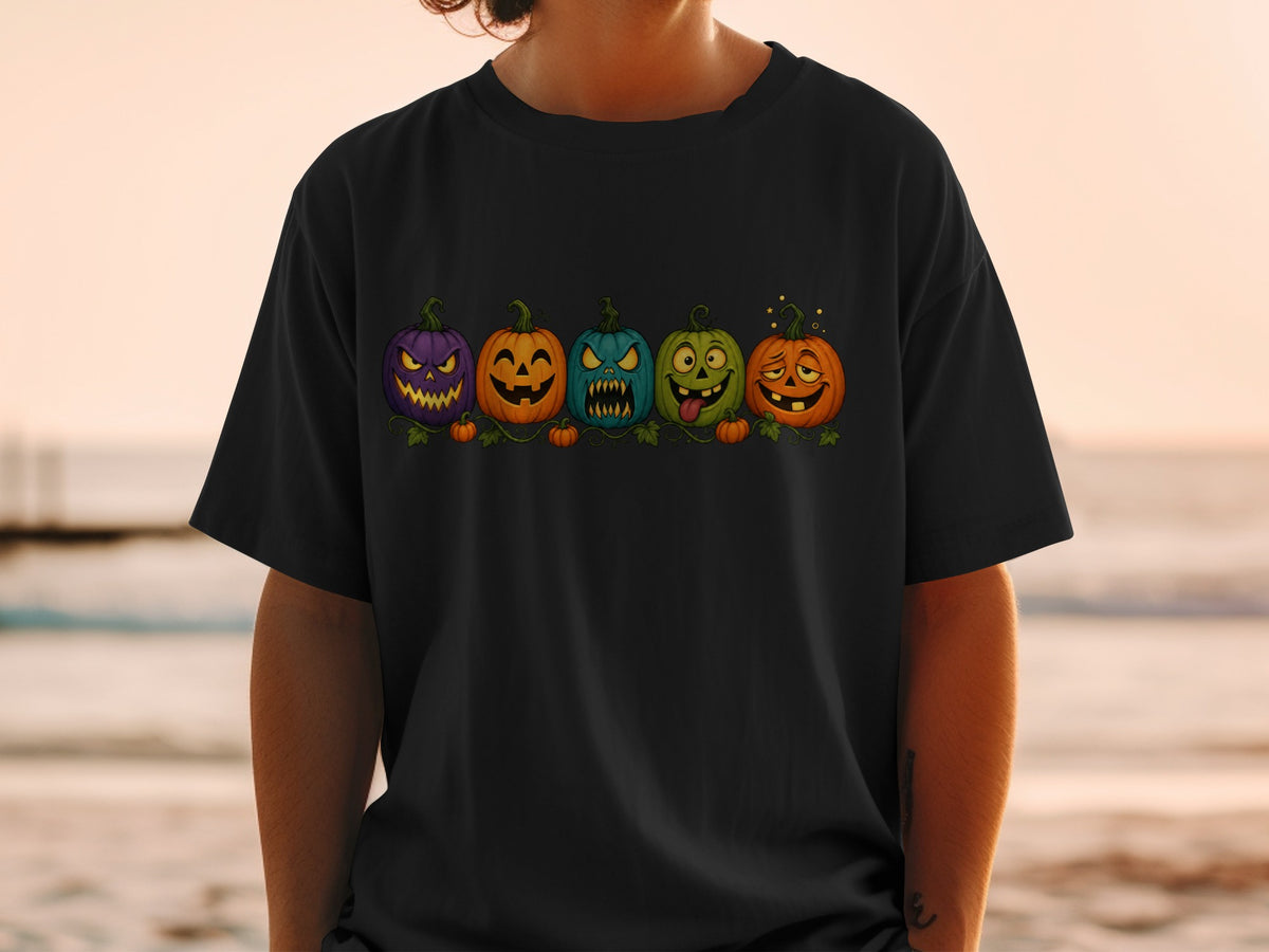 Five cartoon pumpkins with different Halloween expressions displayed on a black t-shirt.