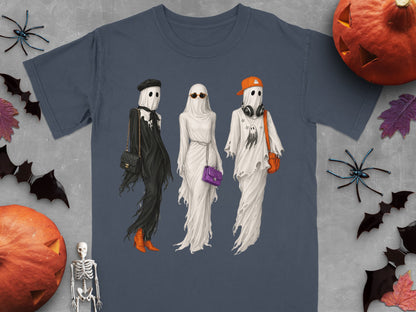 Three ghosts in trendy outfits, on a t-shirt design with Halloween decorations.