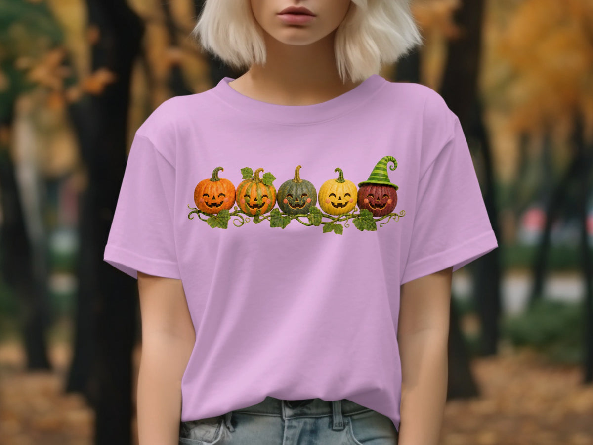 Five jack-o'-lanterns with smiling faces on a vine across a pink t-shirt.