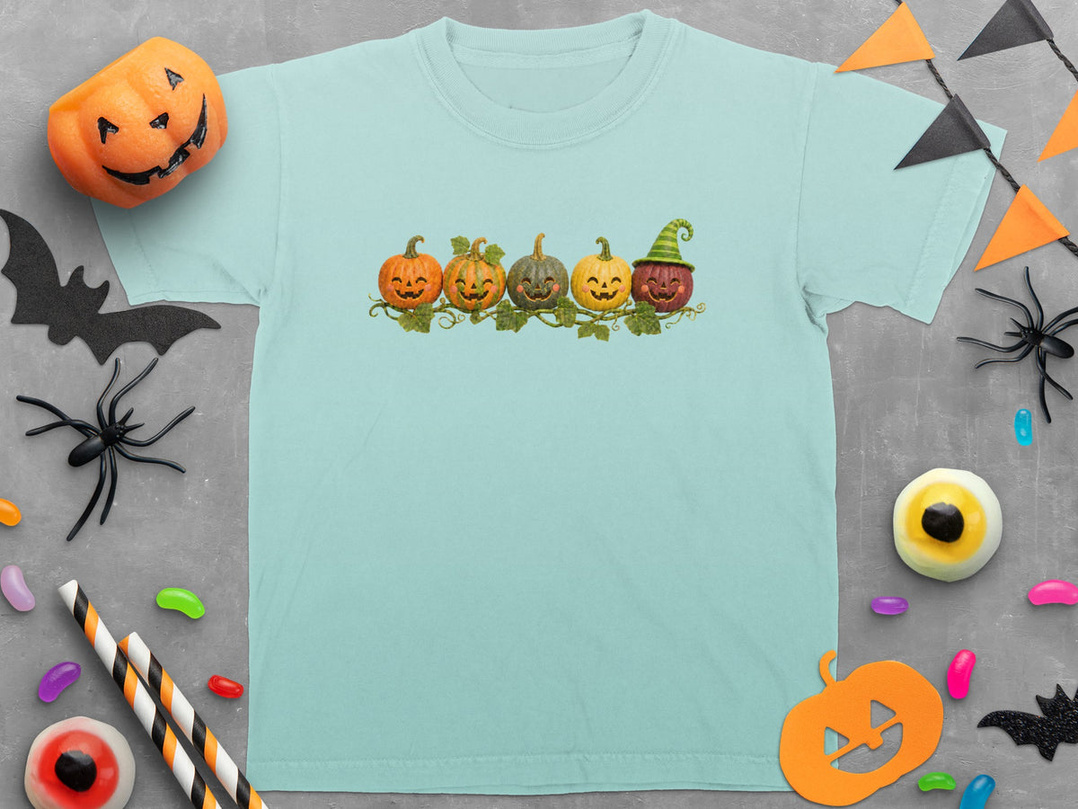 Light blue t-shirt with five smiling pumpkins on a vine and Halloween decorations.
