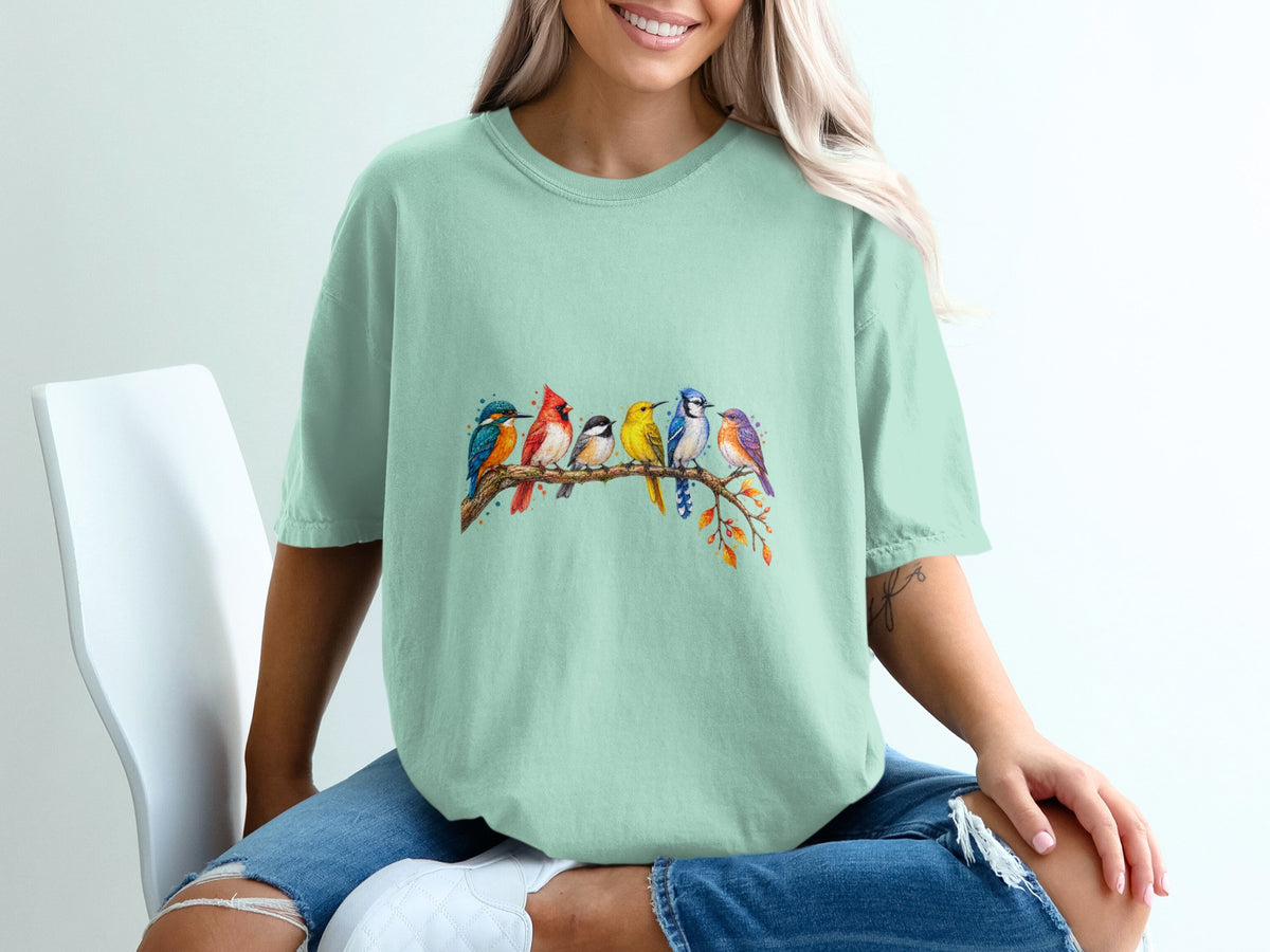 T-shirt with watercolor painting of six colorful birds perched on a branch.