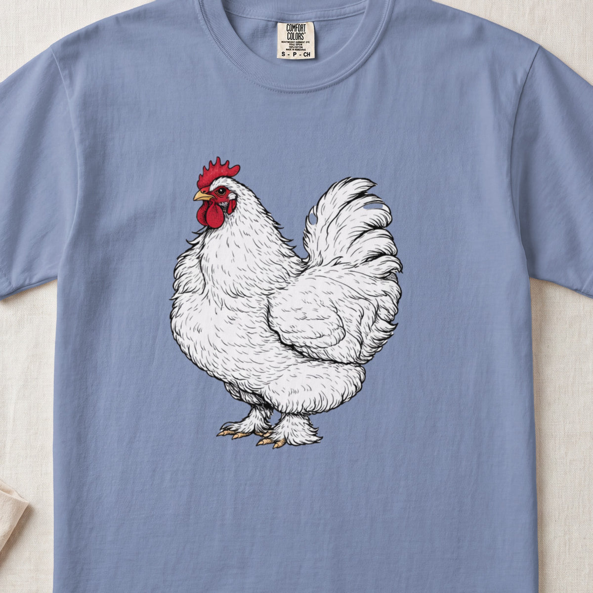 A periwinkle blue t-shirt featuring a vintage line drawing of a white rooster centered on the chest.