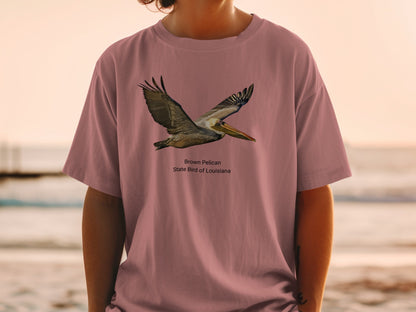 Brown pelican in flight, state bird of Louisiana, printed on a mauve t-shirt.