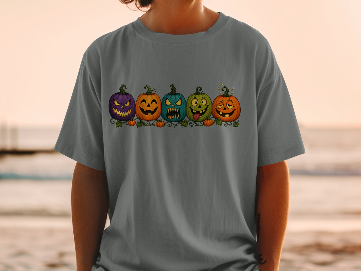 Five cartoon Halloween pumpkins with different facial expressions on a dark gray t-shirt.