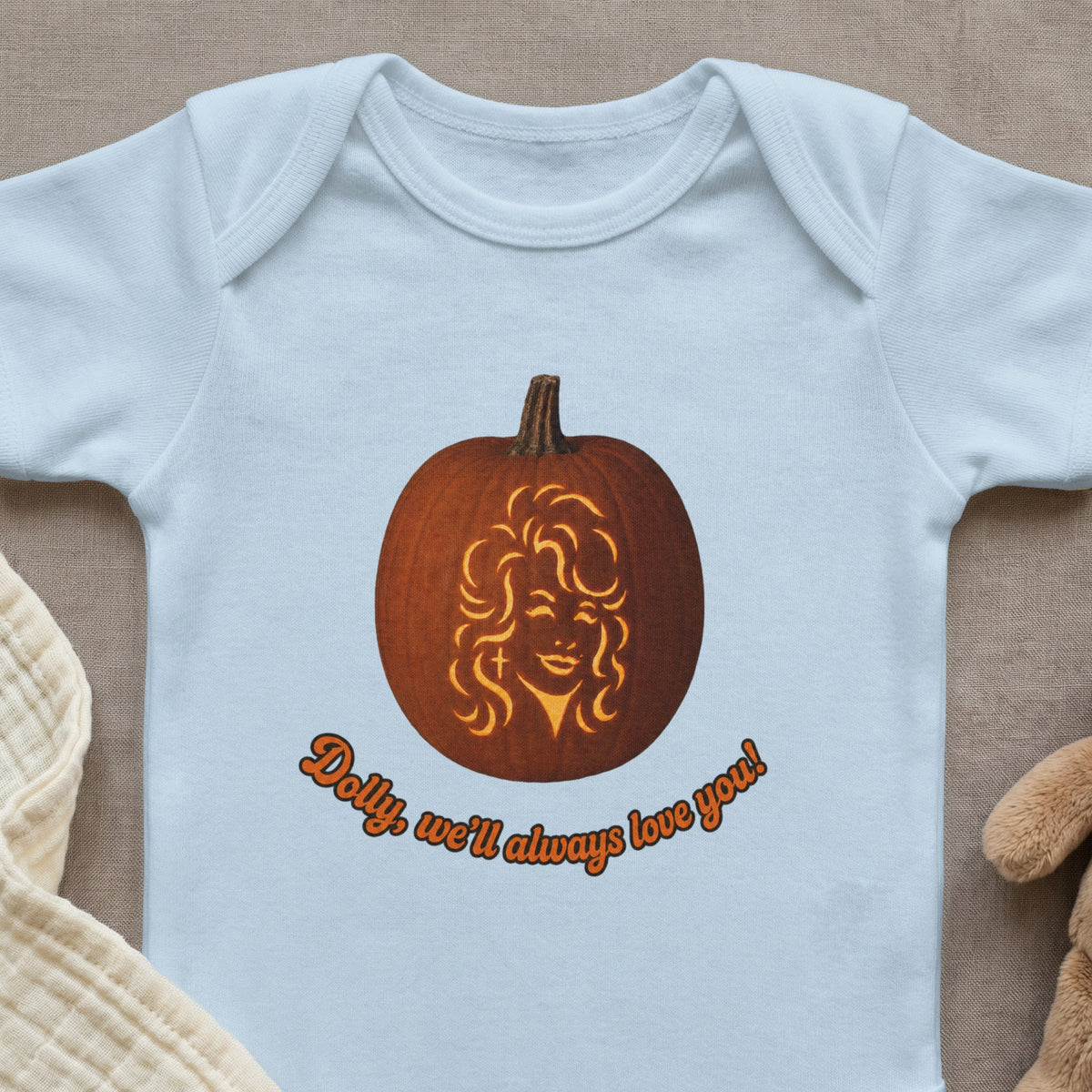 Light blue baby onesie with a pumpkin carved with Dolly Parton's face and text.